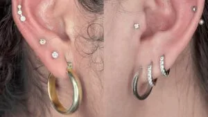 both of the ears have a collection of middle helix, tragus, upper lobe, and lobe piercings 