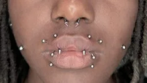 the girl has a collection of piercings including angel fangs, dimples, septum, and snake bites on her face