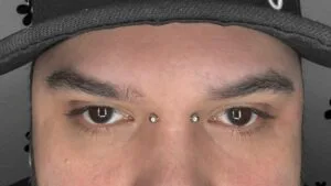 bridge piercing with short barbell jewelry on man's face