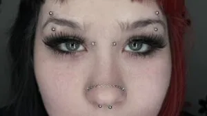 symmetrical eyebrow, bridge, nose, and septum piercings on girl's face 