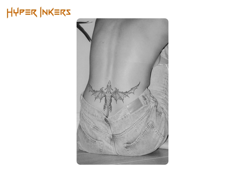 small back tattoo placement - Hyper Inkers A powerful fine-line dragon placed on the lower back, offering a discreet yet fierce symbol of strength and protection.