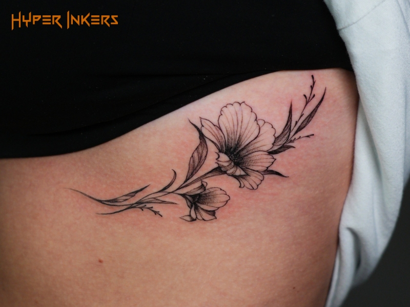 Botanical tattoo of a fine line wildflower stem running along the hip