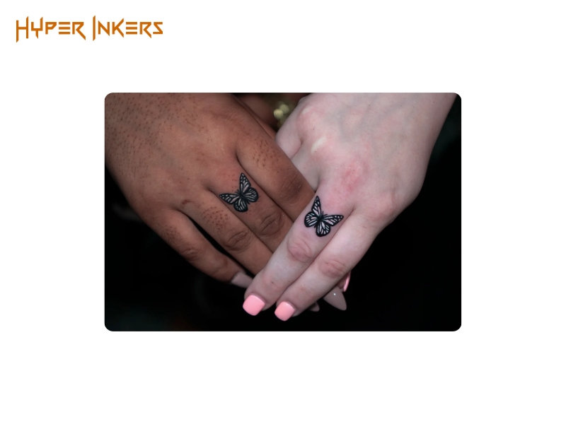 Two matching butterfly tattoos on the middle finger of two hands